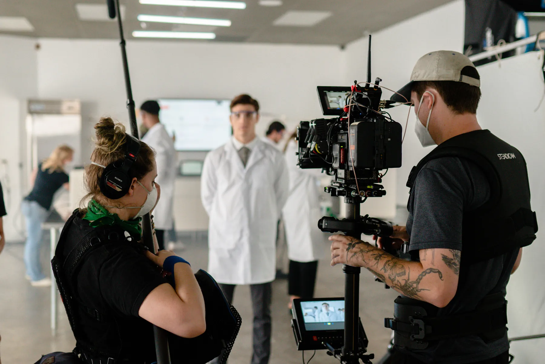 Camera crew in a lab with scientists in white coats